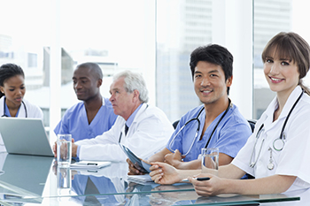 Clinicians sit at a table discussing an medical issue.