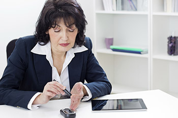 A woman is testing her finger to see if she needs an insulin injection.