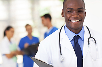 A clincian inn a lab coat looks toward the view with others in the background.