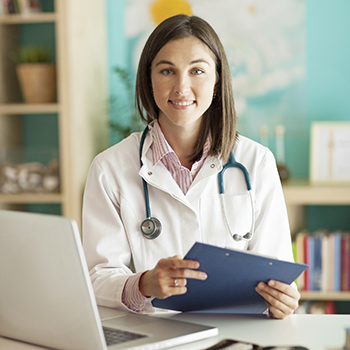 Clinician working on a tablet stands next to a laptop computer in a hospital unit.