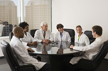 Clinicians meeting across a table to discuss various issues.